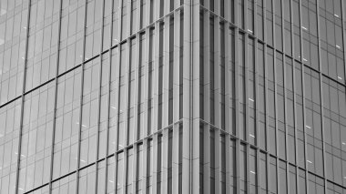 Şehir soyutu - ofis binasının pencereli duvarı. Şehirdeki modern iş binasının detaylı görüntüleri. Bir gökdelenin cam cephesine bakıyorum. Siyah beyaz filtre.