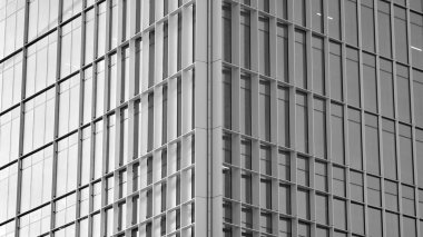 Şehir soyutu - ofis binasının pencereli duvarı. Şehirdeki modern iş binasının detaylı görüntüleri. Bir gökdelenin cam cephesine bakıyorum. Siyah beyaz filtre.