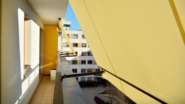 Tentelerle modern mimari bina cephesi. Tente açık, güneş kalkanıyla kaplı balkon.. 