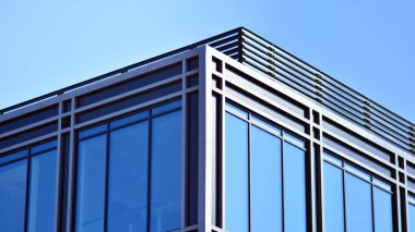 Minimalist cam cephe, büyük şeffaf panelleri tutan çelik iskelet. Çağdaş ticari mimari, dikey geometrik çizgiler. Cam panellerde mavi gökyüzü yansıması