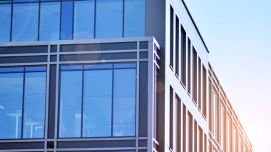 Minimalist cam cephe, büyük şeffaf panelleri tutan çelik iskelet. Çağdaş ticari mimari, dikey geometrik çizgiler. Cam panellerde mavi gökyüzü yansıması