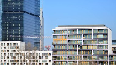 Minimalist cam cephe, büyük şeffaf panelleri tutan çelik iskelet. Çağdaş ticari mimari, dikey geometrik çizgiler. Cam panellerde mavi gökyüzü yansıması