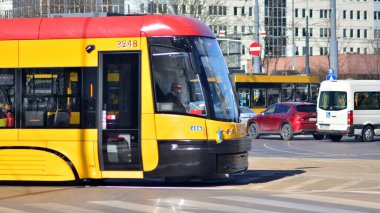 Varşova, Polonya. 28 Mart 2022. Varşova 'nın merkezinde bir tramvayla tren durağı. İnsanlar şehir tramvayından inip biniyorlar. .