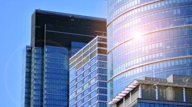 Binanın şeffaf yüzüyle cam bina ve mavi gökyüzü. Yapısal cam duvar mavi gökyüzünü yansıtıyor. Soyut modern mimari parçası. Çağdaş mimari arka plan.