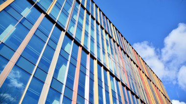 Gökyüzü arka planında cam cepheli modern ofis binası. Yansıtıcı camla kaplı modern bir binanın cam kaplamalı cephesinin soyut görüntüsü..