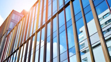Gökyüzü arka planında cam cepheli modern ofis binası. Yansıtıcı camla kaplı modern bir binanın cam kaplamalı cephesinin soyut görüntüsü..
