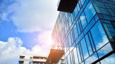 Gökyüzü arka planında cam cepheli modern ofis binası. Yansıtıcı camla kaplı modern bir binanın cam kaplamalı cephesinin soyut görüntüsü..