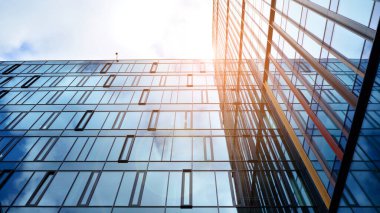 Gökyüzü arka planında cam cepheli modern ofis binası. Yansıtıcı camla kaplı modern bir binanın cam kaplamalı cephesinin soyut görüntüsü..