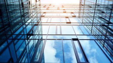 Gökyüzü arka planında cam cepheli modern ofis binası. Yansıtıcı camla kaplı modern bir binanın cam kaplamalı cephesinin soyut görüntüsü..