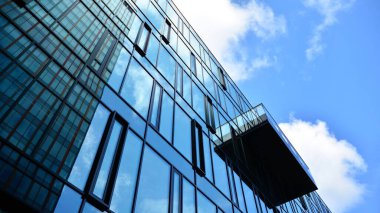Gökyüzü arka planında cam cepheli modern ofis binası. Yansıtıcı camla kaplı modern bir binanın cam kaplamalı cephesinin soyut görüntüsü..