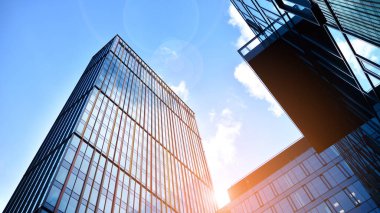 Gökyüzü arka planında cam cepheli modern ofis binası. Yansıtıcı camla kaplı modern bir binanın cam kaplamalı cephesinin soyut görüntüsü..