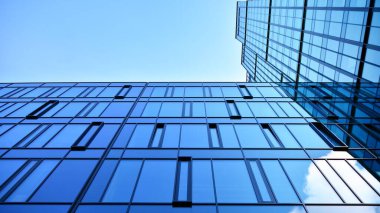 Gökyüzü arka planında cam cepheli modern ofis binası. Yansıtıcı camla kaplı modern bir binanın cam kaplamalı cephesinin soyut görüntüsü..