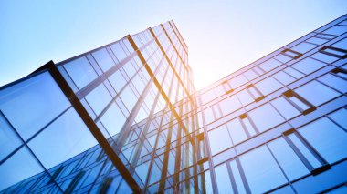 Gökyüzü arka planında cam cepheli modern ofis binası. Yansıtıcı camla kaplı modern bir binanın cam kaplamalı cephesinin soyut görüntüsü..