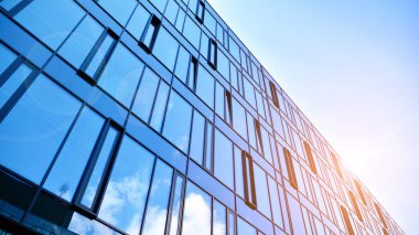 Gökyüzü arka planında cam cepheli modern ofis binası. Yansıtıcı camla kaplı modern bir binanın cam kaplamalı cephesinin soyut görüntüsü..