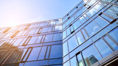 Gökyüzü arka planında cam cepheli modern ofis binası. Yansıtıcı camla kaplı modern bir binanın cam kaplamalı cephesinin soyut görüntüsü..