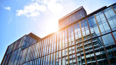 Gökyüzü arka planında cam cepheli modern ofis binası. Yansıtıcı camla kaplı modern bir binanın cam kaplamalı cephesinin soyut görüntüsü..