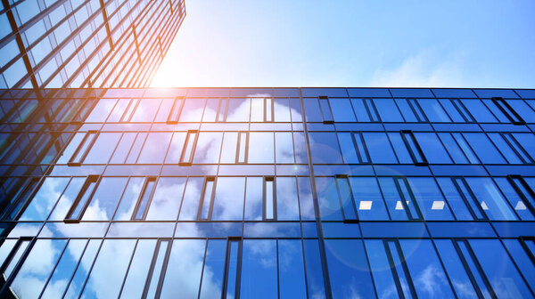 Modern office building with glass facade on a clear sky background. Abstract close up of the glass-clad facade of a modern building covered in reflective plate glass.