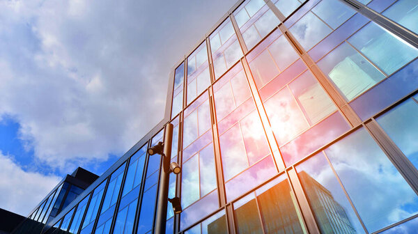  Glass buildings with cloudy blue sky background.  Perspective wide angle view to steel light blue background of glass.  Commercial modern city of future. Business concept of successful  architecture.