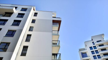 Modern apartman binaları ve şehirde yeni şehir manzarası olan bir yerleşim yeri. Beyaz yüzlü apartman dairesi. Bir sürü kare cam pencereli modern minimalist mimari.