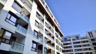 Modern apartman binaları ve şehirde yeni şehir manzarası olan bir yerleşim yeri. Beyaz yüzlü apartman dairesi. Bir sürü kare cam pencereli modern minimalist mimari.