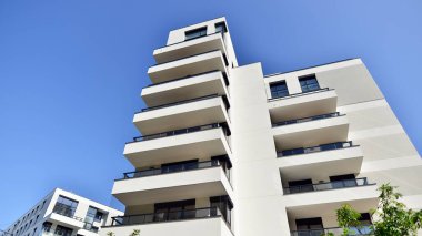 Modern apartman binaları ve şehirde yeni şehir manzarası olan bir yerleşim yeri. Beyaz yüzlü apartman dairesi. Bir sürü kare cam pencereli modern minimalist mimari.