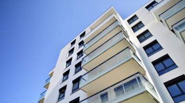 Modern apartman binaları ve şehirde yeni şehir manzarası olan bir yerleşim yeri. Beyaz yüzlü apartman dairesi. Bir sürü kare cam pencereli modern minimalist mimari.