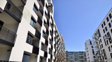 Modern apartman binaları ve şehirde yeni şehir manzarası olan bir yerleşim yeri. Beyaz yüzlü apartman dairesi. Bir sürü kare cam pencereli modern minimalist mimari.