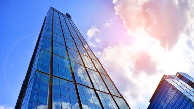 Avrupa 'daki gökdelen binasının siluetine karşı güneş ışığıyla aydınlatılan güzel şehir manzarası. Yüksek cam ve çelik bina manzaralı.