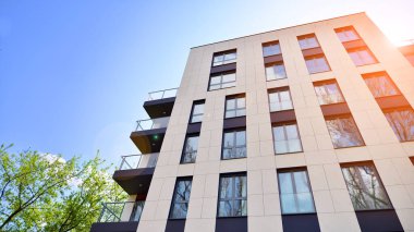 Yeşil yerleşim bölgesinde yeni daireleri olan modern bir yerleşim yeri. Çevre mimarisi. Yeşil ağaç ve yeni apartman. Doğanın ve modernliğin ahengi.