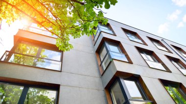 Yeşil yerleşim bölgesinde yeni daireleri olan modern bir yerleşim yeri. Çevre mimarisi. Yeşil ağaç ve yeni apartman. Doğanın ve modernliğin ahengi.