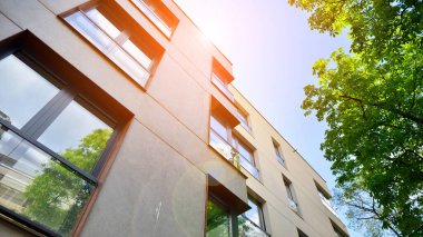 Yeşil yerleşim bölgesinde yeni daireleri olan modern bir yerleşim yeri. Çevre mimarisi. Yeşil ağaç ve yeni apartman. Doğanın ve modernliğin ahengi.