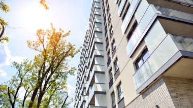 Yeşil yerleşim bölgesinde yeni daireleri olan modern bir yerleşim yeri. Çevre mimarisi. Yeşil ağaç ve yeni apartman. Doğanın ve modernliğin ahengi.