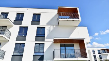Balkonları ve bulutlu mavi gökyüzü olan beyaz bir yerleşim yerinin parçası. Güneşli bir günde modern apartmanda mimari detaylar.