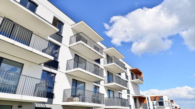 Balkonları ve bulutlu mavi gökyüzü olan beyaz bir yerleşim yerinin parçası. Güneşli bir günde modern apartmanda mimari detaylar.