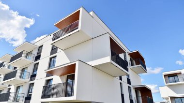 Balkonları ve bulutlu mavi gökyüzü olan beyaz bir yerleşim yerinin parçası. Güneşli bir günde modern apartmanda mimari detaylar.