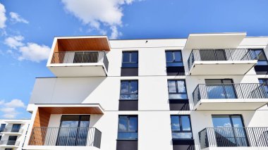 Balkonları ve bulutlu mavi gökyüzü olan beyaz bir yerleşim yerinin parçası. Güneşli bir günde modern apartmanda mimari detaylar.