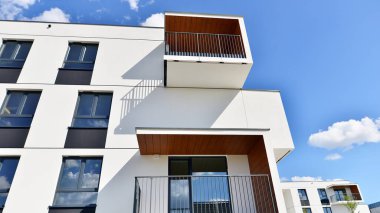 Balkonları ve bulutlu mavi gökyüzü olan beyaz bir yerleşim yerinin parçası. Güneşli bir günde modern apartmanda mimari detaylar.