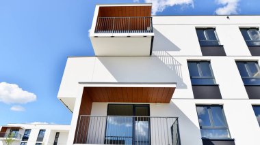 Balkonları ve bulutlu mavi gökyüzü olan beyaz bir yerleşim yerinin parçası. Güneşli bir günde modern apartmanda mimari detaylar.