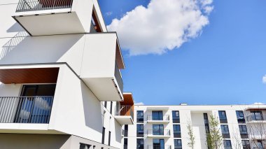 Balkonları ve bulutlu mavi gökyüzü olan beyaz bir yerleşim yerinin parçası. Güneşli bir günde modern apartmanda mimari detaylar.