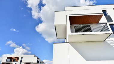 Balkonları ve bulutlu mavi gökyüzü olan beyaz bir yerleşim yerinin parçası. Güneşli bir günde modern apartmanda mimari detaylar.