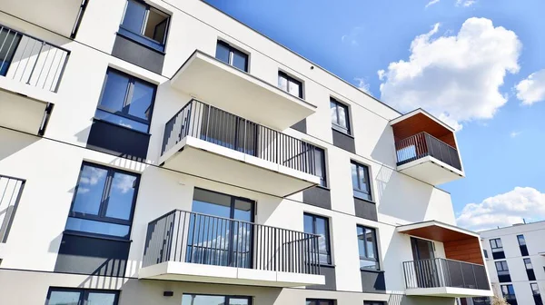 Balkonları ve bulutlu mavi gökyüzü olan beyaz bir yerleşim yerinin parçası. Güneşli bir günde modern apartmanda mimari detaylar.