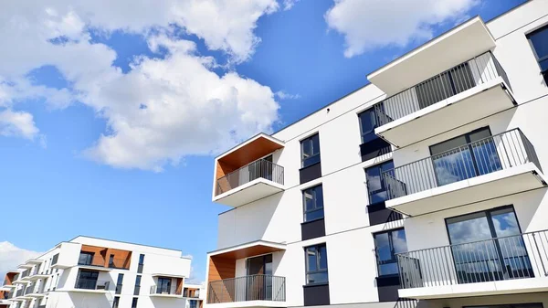 Balkonları ve bulutlu mavi gökyüzü olan beyaz bir yerleşim yerinin parçası. Güneşli bir günde modern apartmanda mimari detaylar.