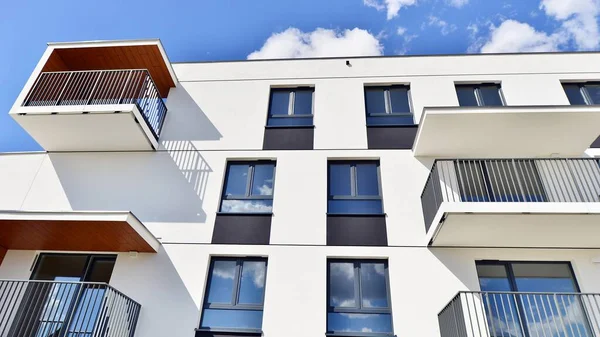 Balkonları ve bulutlu mavi gökyüzü olan beyaz bir yerleşim yerinin parçası. Güneşli bir günde modern apartmanda mimari detaylar.