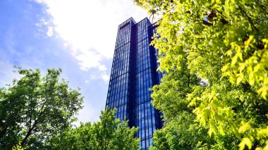 Taze yeşil ağaçlar ve ofis binası, iş konsepti. Modern şehir konseptinde yankı oluşturma.  