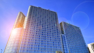 Güneşin uzun, modern bir binanın cam cephesindeki yansıması. İşletme inşaat endüstrisi ve emlak finansmanı. Güneşli şehir manzarası. 