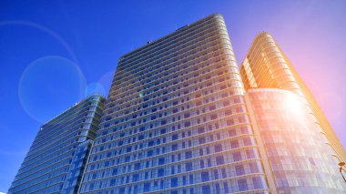 Güneşin uzun, modern bir binanın cam cephesindeki yansıması. İşletme inşaat endüstrisi ve emlak finansmanı. Güneşli şehir manzarası. 