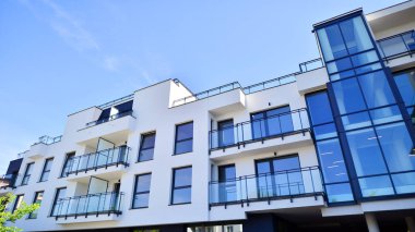 Parlak yüzlü apartman dairesi. Bir sürü kare cam pencere ve balkonu olan modern minimalist mimari.