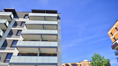 Parlak yüzlü apartman dairesi. Bir sürü kare cam pencere ve balkonu olan modern minimalist mimari.