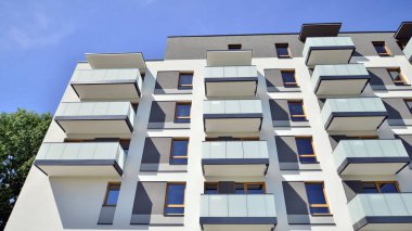 Parlak yüzlü apartman dairesi. Bir sürü kare cam pencere ve balkonu olan modern minimalist mimari.