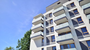 Parlak yüzlü apartman dairesi. Bir sürü kare cam pencere ve balkonu olan modern minimalist mimari.